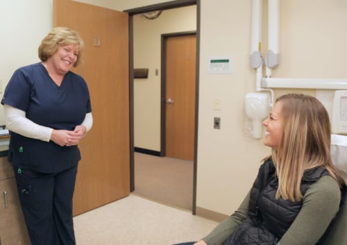 Dental staff talks with patient during an initial visit | greater michigan oral surgeons implant center